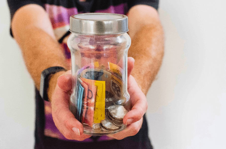 adult hands holding glass jar with australian notes